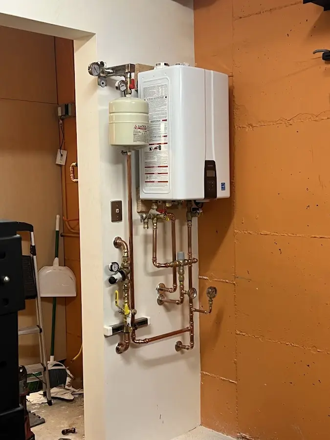 Plumbing technician inspecting water heater connections in Center Point